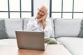 Senior man using laptop at home sitting on the sofa sleeping tired dreaming and posing with hands together while smiling with Royalty Free Stock Photo