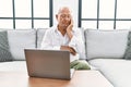 Senior man using laptop at home sitting on the sofa thinking looking tired and bored with depression problems with crossed arms Royalty Free Stock Photo