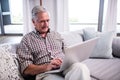 Senior man using laptop in living room Royalty Free Stock Photo