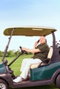 Senior man using mobile phone and driving cart Royalty Free Stock Photo