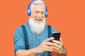 Senior man using mobile smartphone while listening music playlist with wireless headphones - Mature hipster male having fun Royalty Free Stock Photo