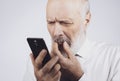 Senior man using a phone and having eyesight problems Royalty Free Stock Photo