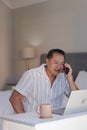 Senior man using smartphone and laptop at home, enjoying conversation Royalty Free Stock Photo