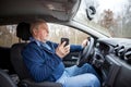 Senior man using a smartphone while riding his new, modern car, transportation concept Royalty Free Stock Photo