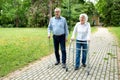 Senior man using a walking cane accompanied by a senior lady strolling with folding walker Royalty Free Stock Photo