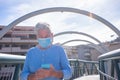 Senior man walking and looking at cellphone, wearing surgical mask to protect from coronavirus contagion