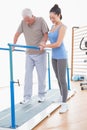 Senior man walking with parallel bars and coach help Royalty Free Stock Photo