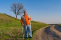 Senior man with walking stick standing on an earth road