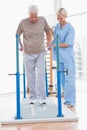 Senior man walking with therapist help