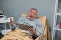 A senior man watching sports games on his tab in a nurcing home