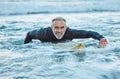 Senior man, water and sports surfer on a beach with smile training for fitness and health or hobby in the outdoors Royalty Free Stock Photo