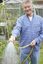 Senior Man Watering Garden With Hosepipe