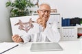 Senior man wearing doctor uniform doing rorscharch test at clinic Royalty Free Stock Photo
