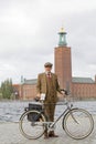 Senior man wearing old fashioned tweed suit and hat holding a retro bicycle in front of Stockholm City Hall Royalty Free Stock Photo