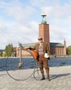 Senior man wearing old fashioned tweed suit holding a high wheeler bicycle in front of Stockholm City Hall Royalty Free Stock Photo