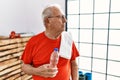 Senior man wearing sportswear and towel at the gym looking to side, relax profile pose with natural face and confident smile Royalty Free Stock Photo