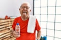 Senior man wearing sportswear and towel at the gym sticking tongue out happy with funny expression Royalty Free Stock Photo