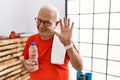 Senior man wearing sportswear and towel at the gym waiving saying hello happy and smiling, friendly welcome gesture Royalty Free Stock Photo