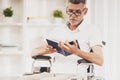 Senior Man in Wheelchair Reading Book at Home. Royalty Free Stock Photo