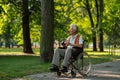 Senior man in wheelchair spending free time outdoors in nature, watching forest animals through binoculars. Royalty Free Stock Photo