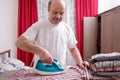 Senior man at home ironing his clothes