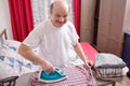 Senior man at home ironing his clothes