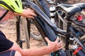 A senior man with white hair and beard checking the battery  of his black electric bicycle. Outdoor footpath. Yellow helmet Royalty Free Stock Photo