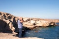 Senior man with white hair standing on the cliff with a blue sea looking with binoculars Royalty Free Stock Photo