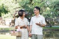 Senior man and wife holding a picnic basket walking among the green trees in the park A retired couple in their 60s