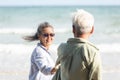 Senior man and woman couple holding hands walking to the beach sunny with bright blue sky Royalty Free Stock Photo