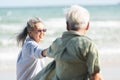 Senior man and woman couple holding hands walking to the beach sunny with bright blue sky Royalty Free Stock Photo