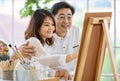 Senior man and woman couple, husband and wife, painting image together in home gallery with warm and happy circumstance. The man