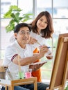 Senior man and woman couple, husband and wife, painting image together in home gallery with warm and happy circumstance. Idea for