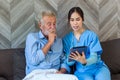 Senior man and woman making online call using tablet. Nurse Helps Senior man Video Chat On Tablet In Nursing Home Or At Home Royalty Free Stock Photo