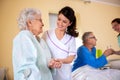 Senior man and senior woman nursing home residents assisted by medical staff of the residential facility