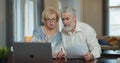 Senior man and woman paying bills and managing budget. Mature worried couple sitting and managing expenses at home. Royalty Free Stock Photo