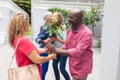 Senior man and woman welcoming multiracial friends at entrance during house party Royalty Free Stock Photo