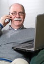 Senior man working on laptop and calling by phone