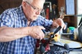 Senior Man Working On Model Radio Controlled Aeroplane In Shed At Home