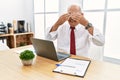 Senior man working at the office using computer laptop covering eyes with hands smiling cheerful and funny Royalty Free Stock Photo