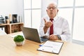 Senior man working at the office using computer laptop looking at the camera blowing a kiss with hand on air being lovely and sexy Royalty Free Stock Photo