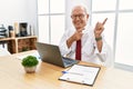 Senior man working at the office using computer laptop smiling and looking at the camera pointing with two hands and fingers to Royalty Free Stock Photo