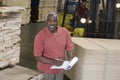 Senior Man Writing On A Clip Board With Man Driving Forktruck At Warehouse Royalty Free Stock Photo