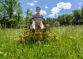 Senior man on zero turn lawnmower in meadow