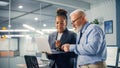 Senior Manager Talking to Experienced Confident Businessman while Using Laptop Computer in Office Royalty Free Stock Photo