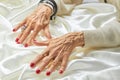 Senior manicured hands with jewelry on silk. Royalty Free Stock Photo