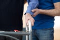 Senior Mans Hands On Walking Frame With Care Worker In Backgrou