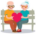 Senior married couple sits on a bench holding a heart symbol