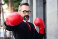 Senior mature businessman wearing red boxing gloves or mitt punch, metaphors about fight business for successful, elderly man