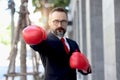 Senior mature businessman wearing red boxing gloves or mitt punch, metaphors about fight business for successful, elderly man